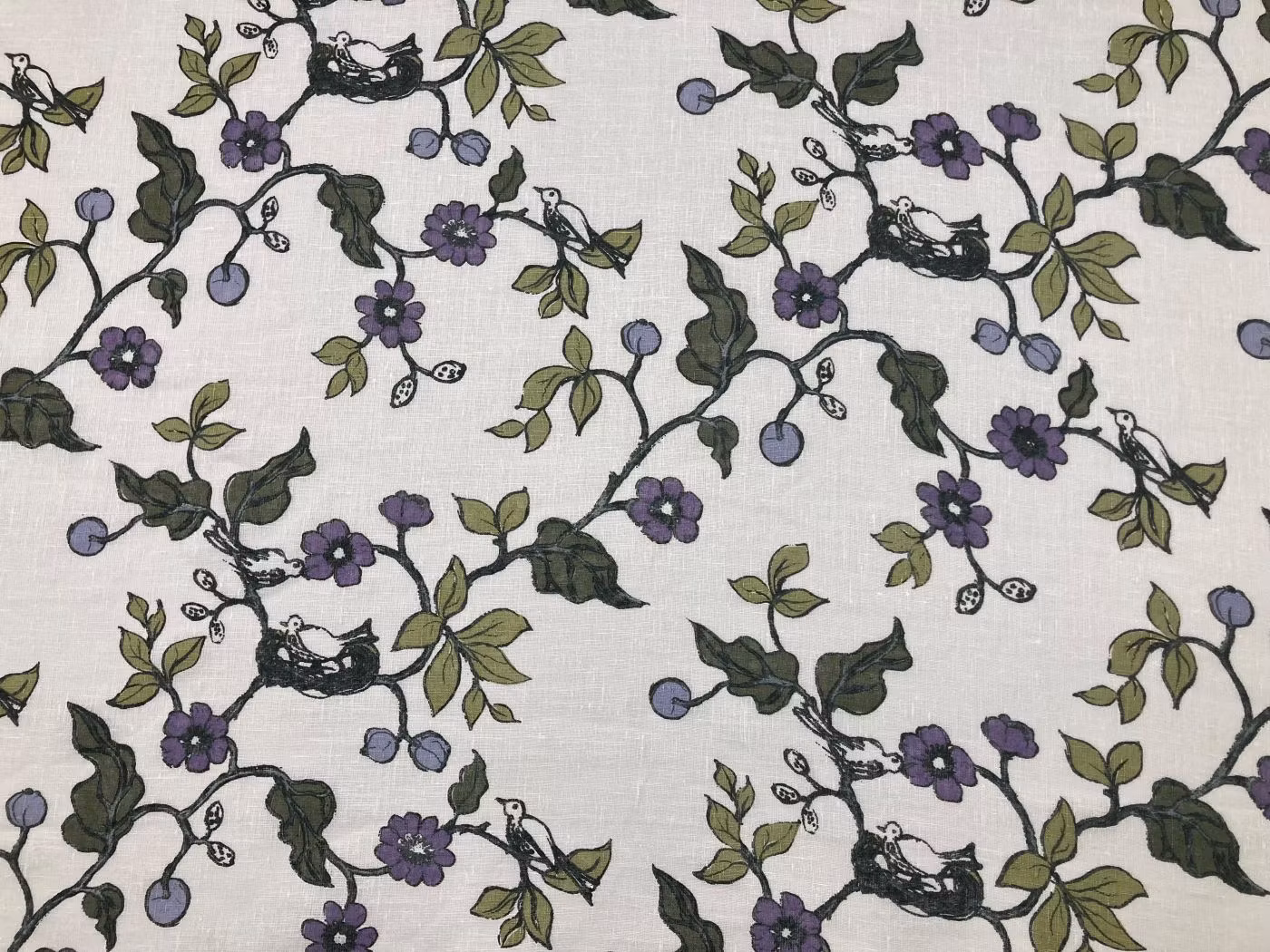 Fågelbo glesvävt hellinne med blommor i lila och gröna toner på naturvit botten.