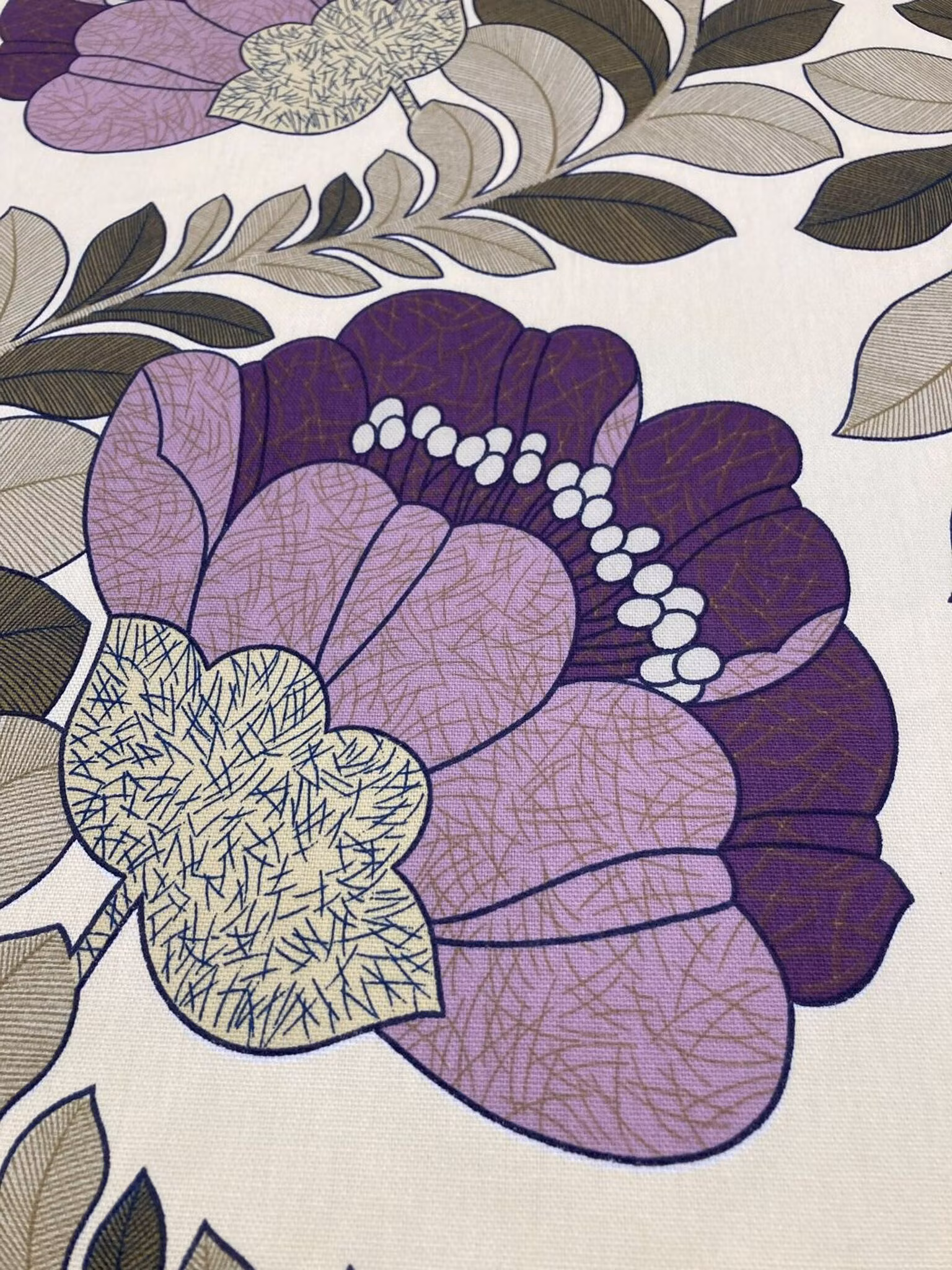 Närbild av Retro lila som visar de stora stiliserade blommorna och den kraftiga tygkvaliteten.
