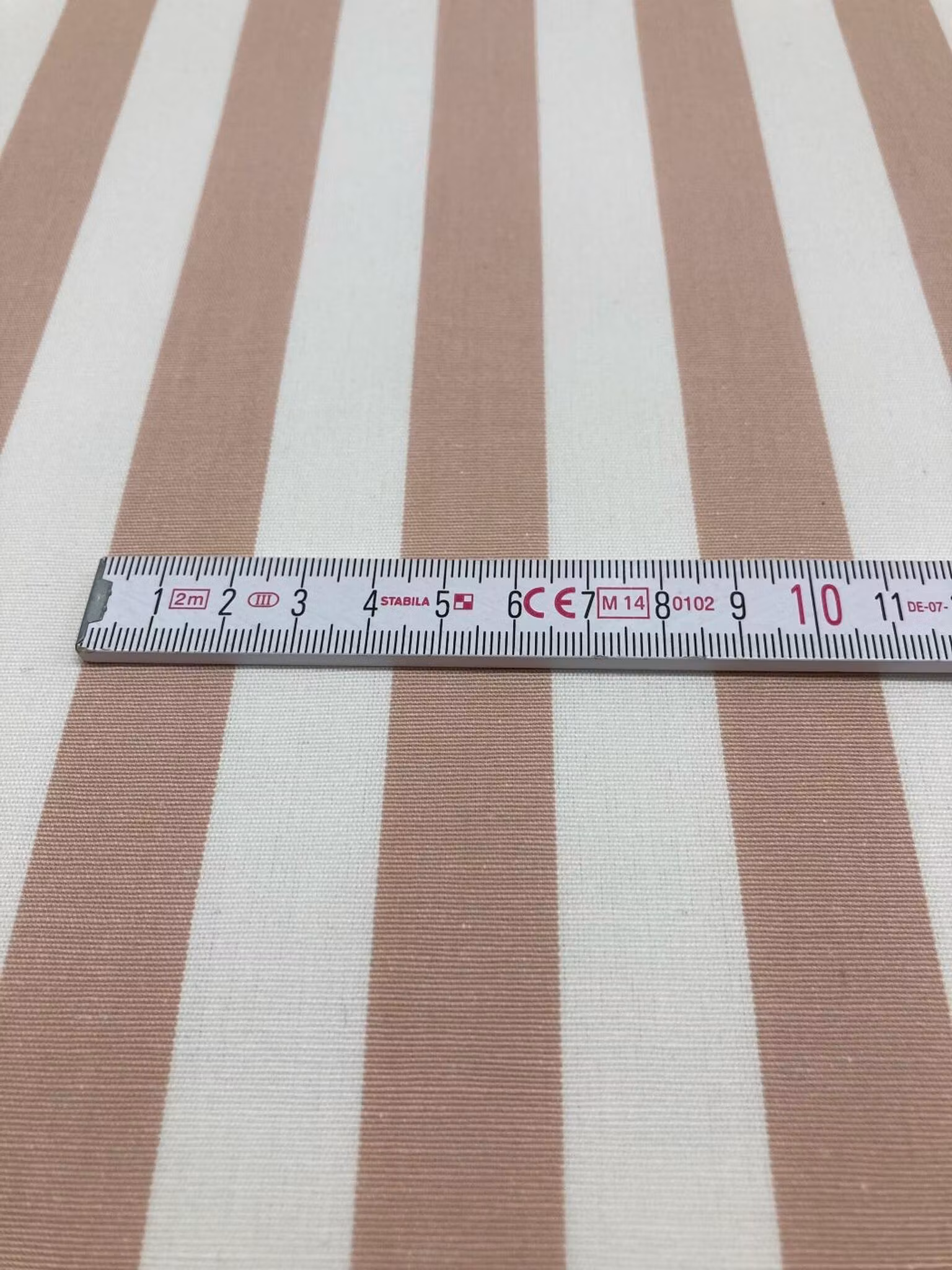 Närbild av Ekedal rosa rand med måttband som visar de cirka 2 cm breda ränderna.