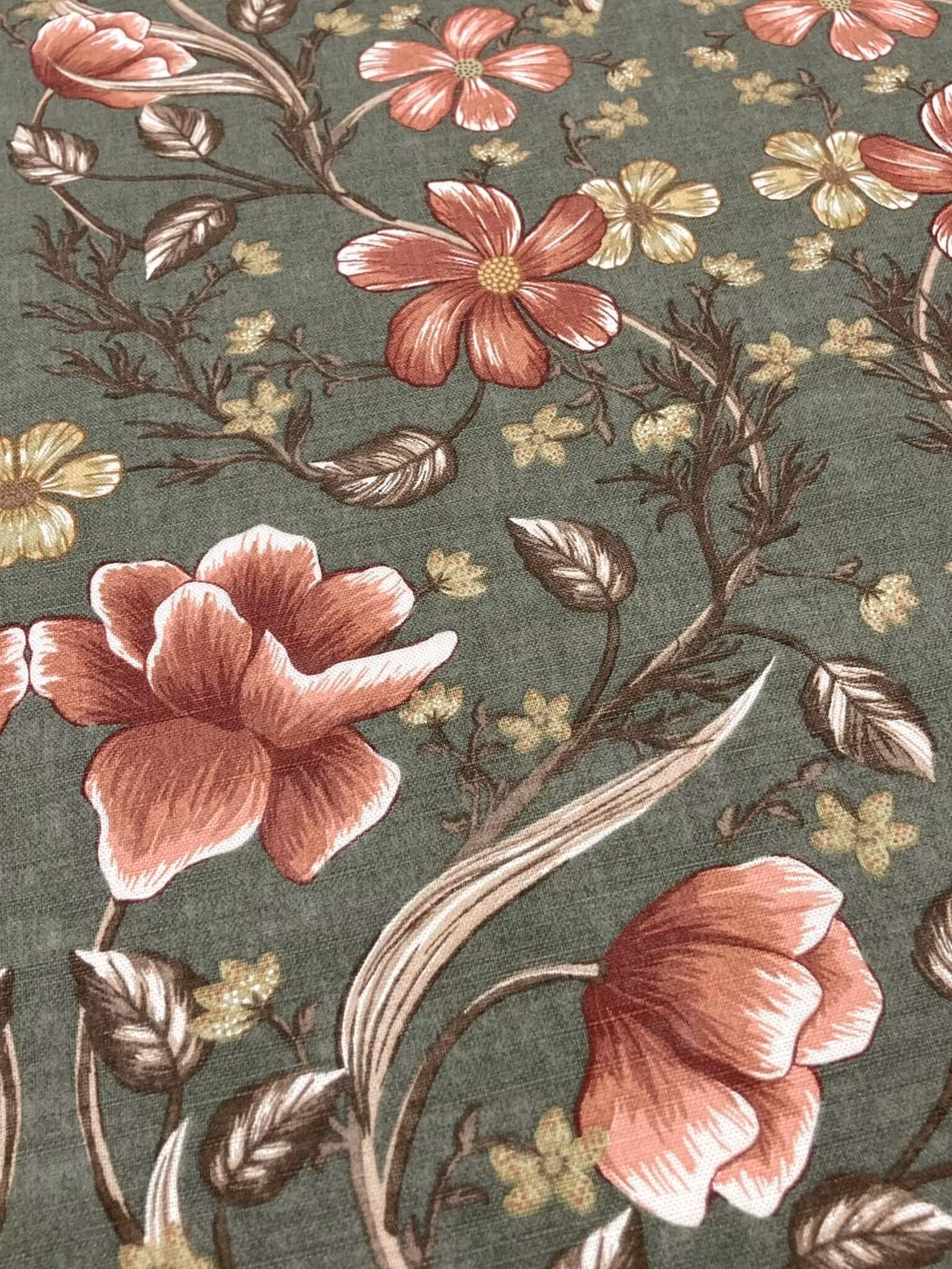 Närbild på Rhode gardin i bomull med blommor och blad i rost, beige och gröna toner