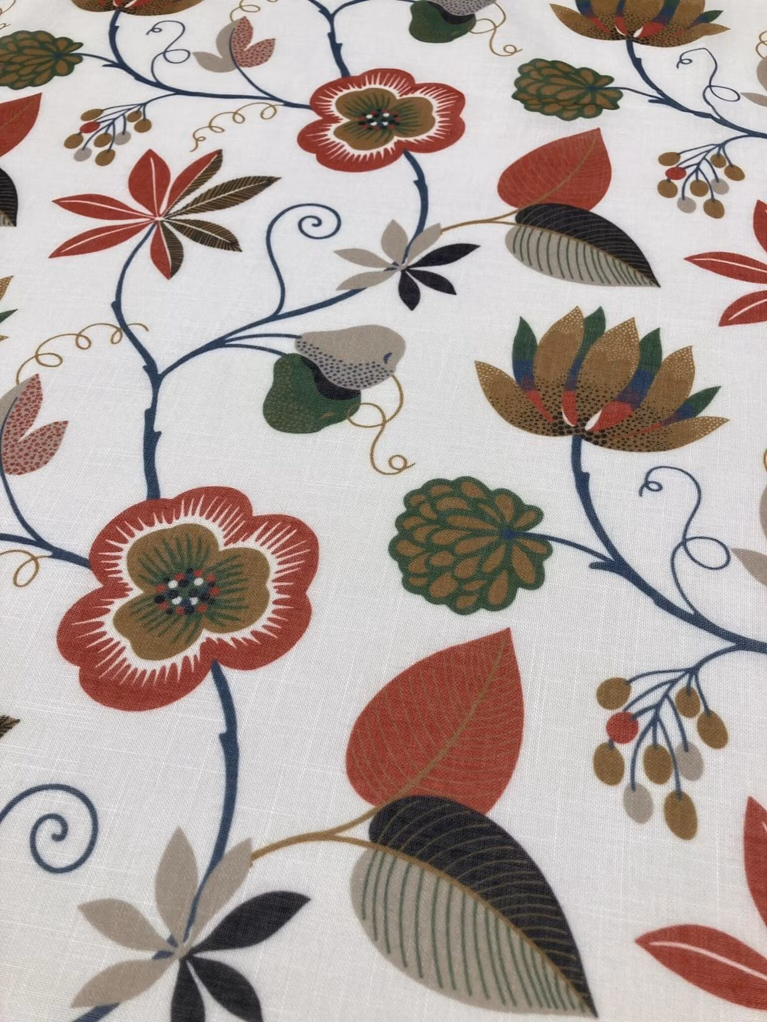Närbild på Sigrid gardin med blommor och blad i rost, grönt, senapsgult och mörkblått