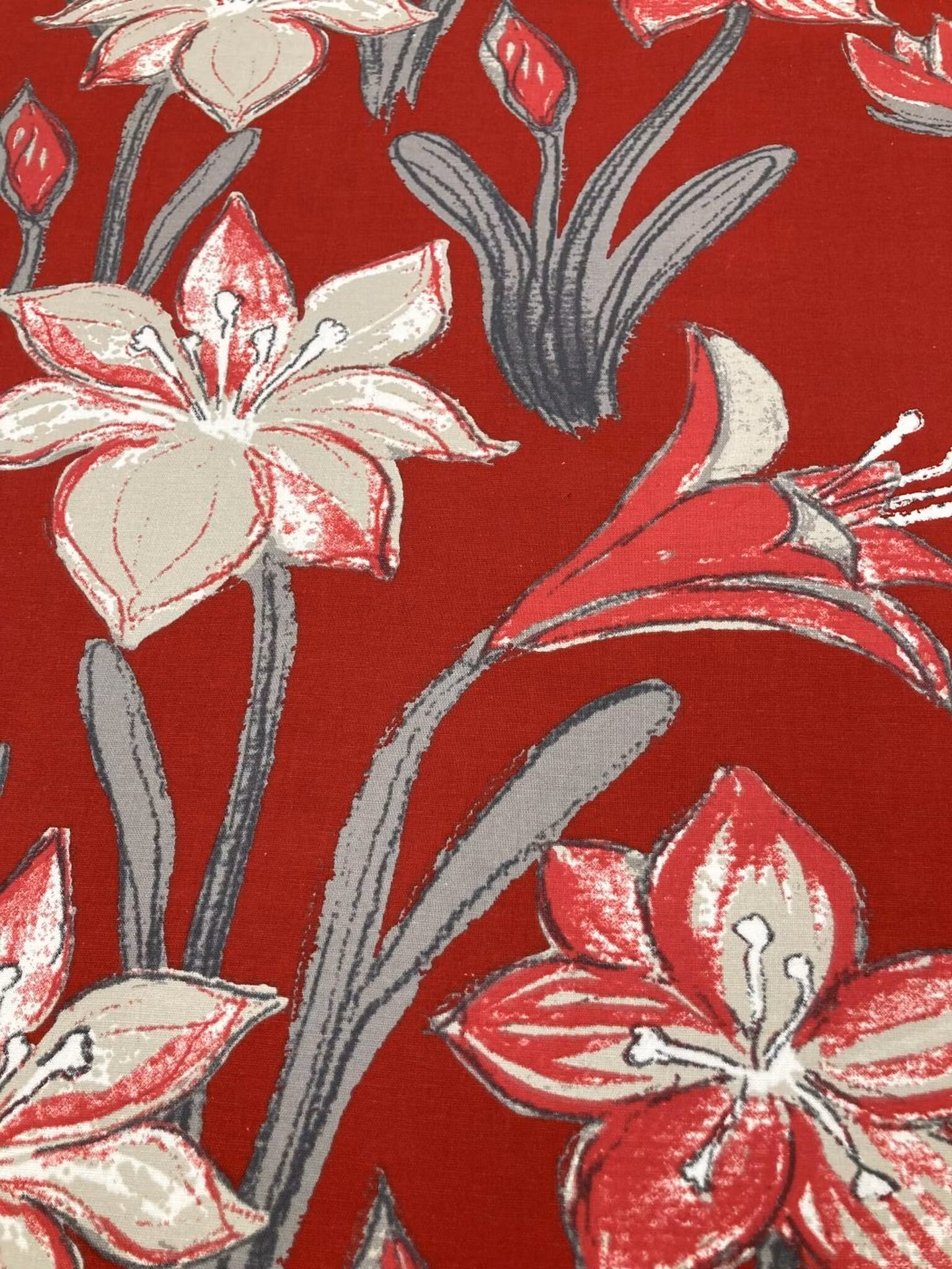 Närbild av Sandblom Röd med modernt blommönster i sandbeige, mörkrött och grått på röd botten.