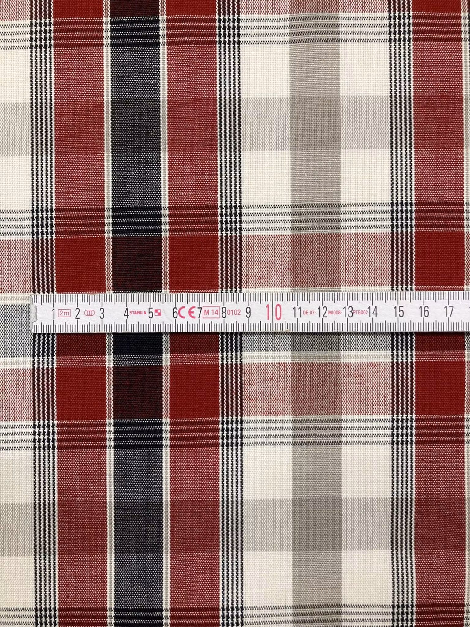 Närbild av Rut, rutigt bomullstyg med korsande vävda ränder i rött, svart, vitt och beige.