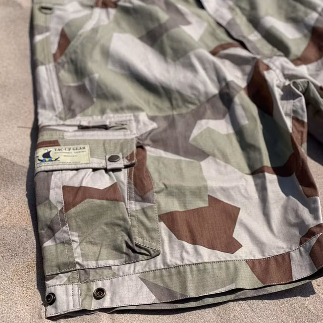 A pair of Camp Shorts M90K Desert from TAC-UP GEAR  lying flat on the sand