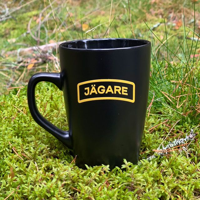 En Kaffemugg JÄGARE Black i skogen på mossa
