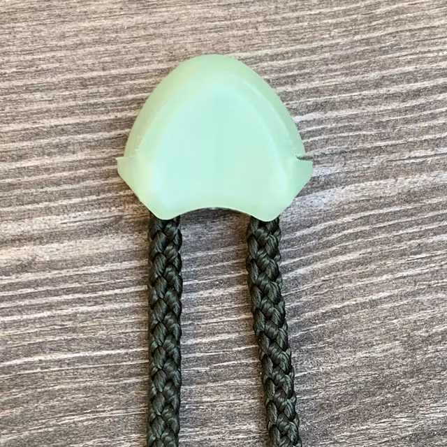 Cord End Glow In The Dark fully mounted on green string
