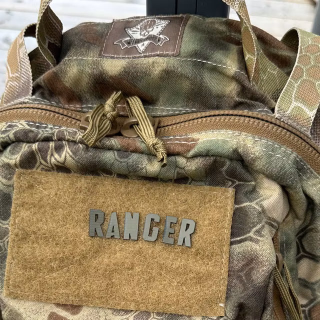 RANGER patch from the DIY Alphabet and Number Hook Patch Set Green mounted on a camouflage backpack