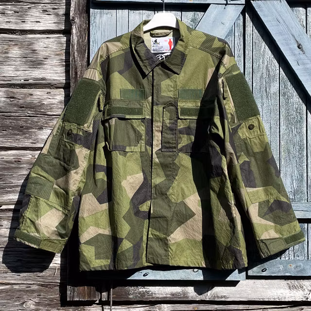A closer look at our popular Field Shirt M90 hanging on a wooded buildning as background