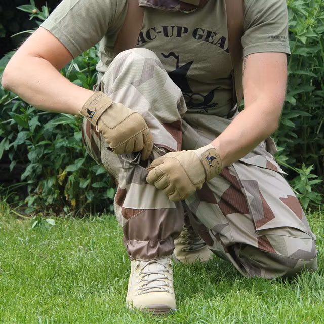 Kneeling wearing a pair of Field Trousers M90K Desert showing the pocket down by the boot.