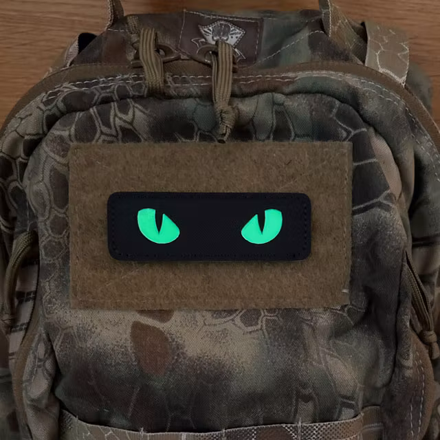 Glow Eyes Patch illuminated on a camouflage backpack in low light