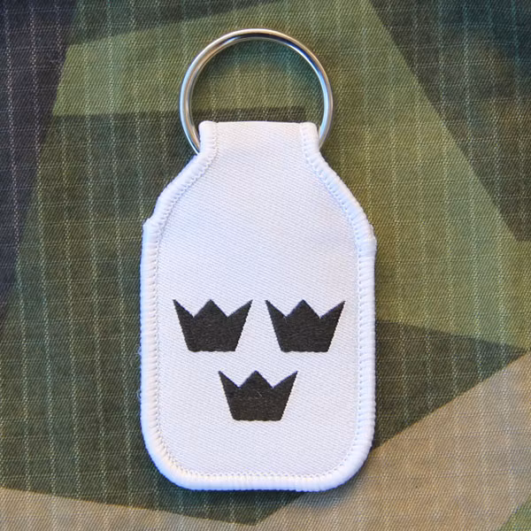 Keyring White With Crowns in a M90 camouflage background.