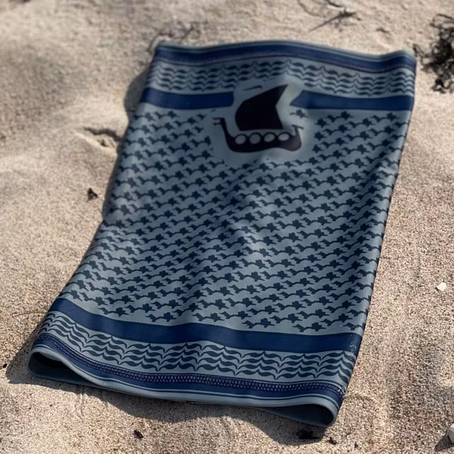 A Neck Tube Shemagh Navy Grey from TAC-UP GEAR lying flat on a sandy beach seen from above