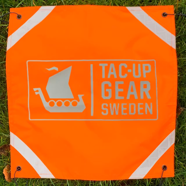 Orange Ruck Signal Panel Marker seen straight on, light reflecting.