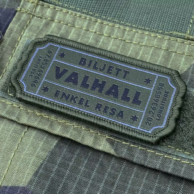 En Biljett Valhall Militärgrön monterad med kardborre på en M90 Shirt