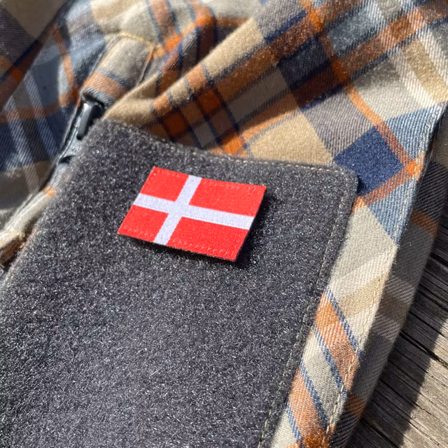 A Denmark Flag Hook Patch Small from TAC-UP GEAR mounted on loop fabric on a shirt