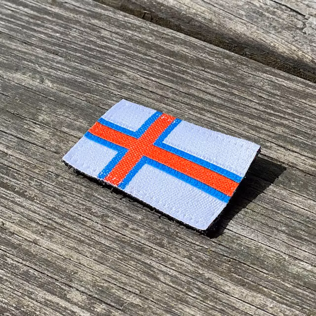 Faroese Flag Hook Patch Small seen from an angle lying on wooded floor
