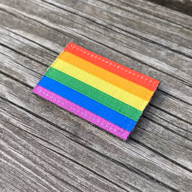 Rainbow Flag Hook Patch Small lying flat on wooded plank seen from an angle