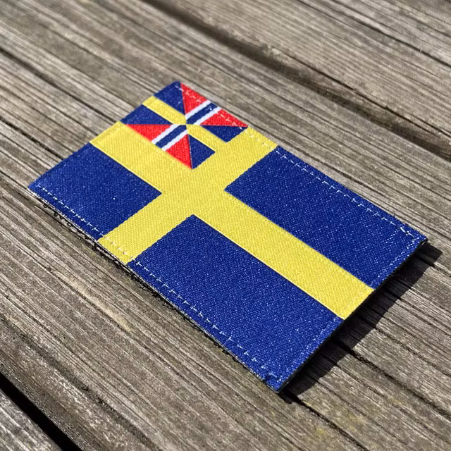 Sveriges handelsflagga 1844–1905 från TAC-UP GEAR sett från sidan liggandes på brädor