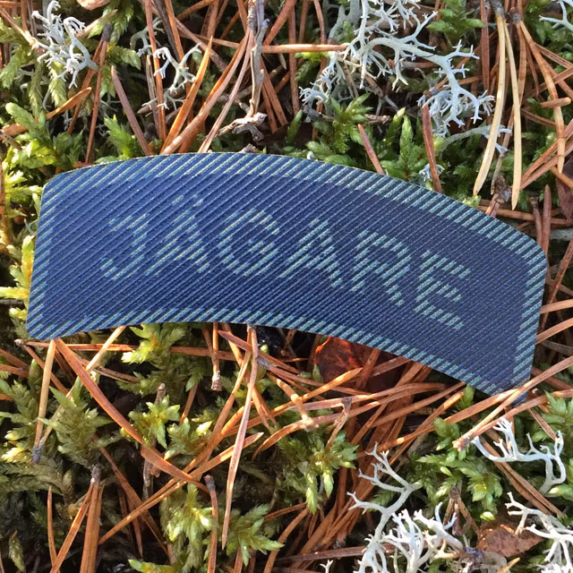 Utomhus foto på ett IR - JÄGARE Dual Grön/Svart märke med Svensk mossig skogsbakgrund.