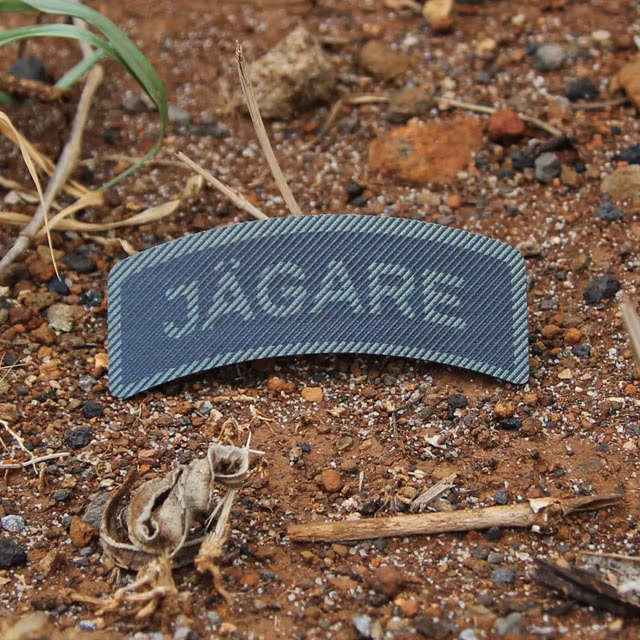 IR - JÄGARE Dual Grön/Svart produktbild med röd brun jord i bakgrunden.