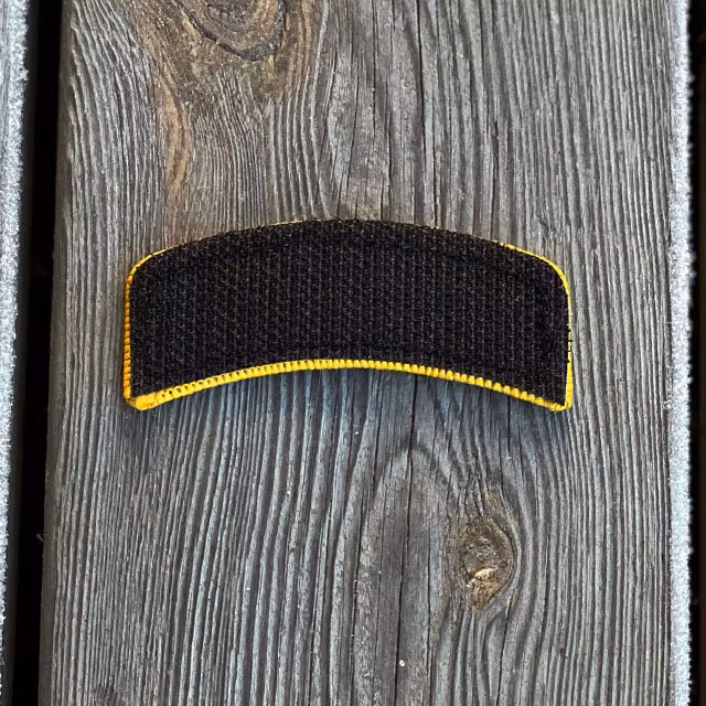 A JÄGARE Hook Patch Orange/Black seen from the back showing the hook fabric