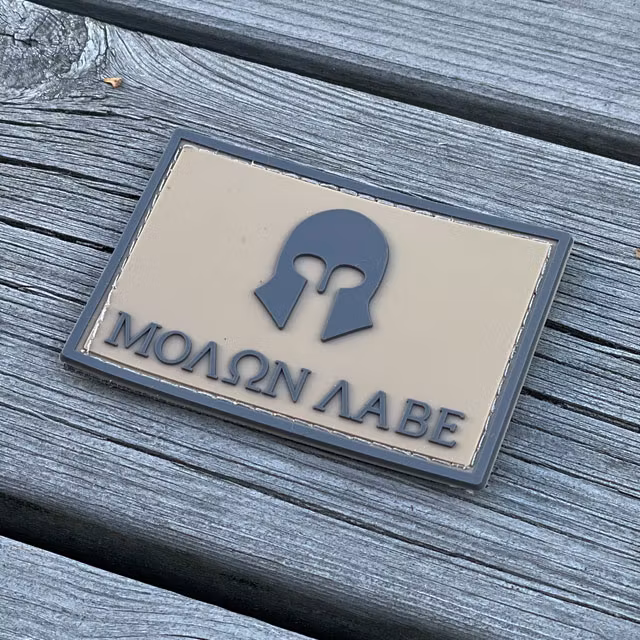 Molon Labe Coyote PVC Hook Patch with a wooden floor background from TAC-UP GEAR