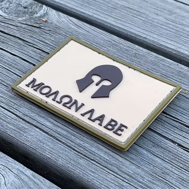 A Molon Labe Multi Tan PVC Patch from TAC-UP GEAR seen from an angle