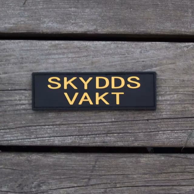 Skyddsvakt PVC Avlång Kardborremärke mot en bakgrund av trä.