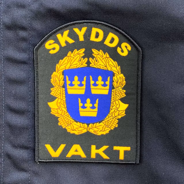 Skyddsvakt Rundad Kardborremärke närbild mot blå jacka