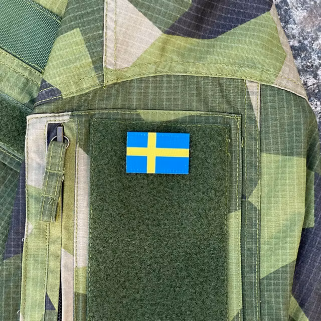 A Sweden Flag Hook Patch Arm seen mounted on a Fieldshirt in M90 camouflage