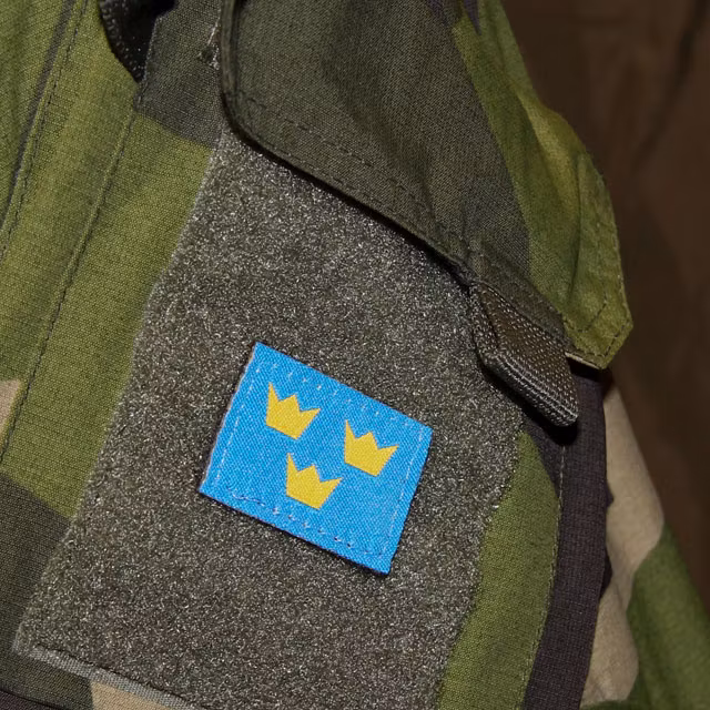 A Three Crowns Morale Patch is mounted on a NCWR M90 Camouflage jacket.