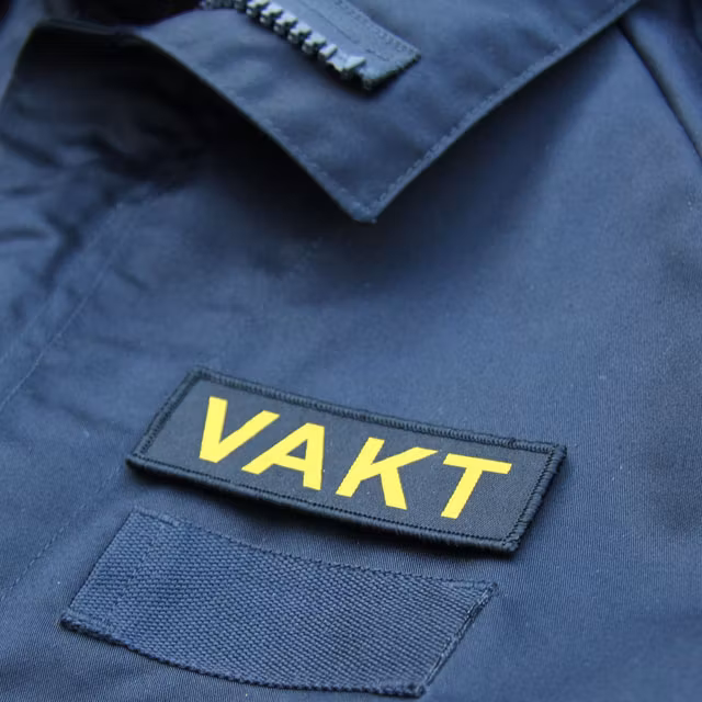 VAKT Kardborremärke mot blå bakgrund.