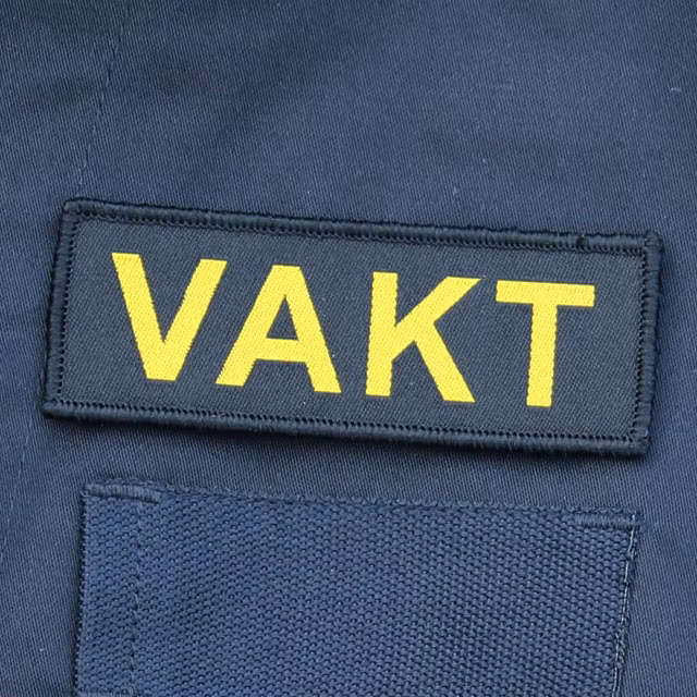 Ett VAKT Kardborremärke mot en bakgrund av Marinens uniformsjacka.