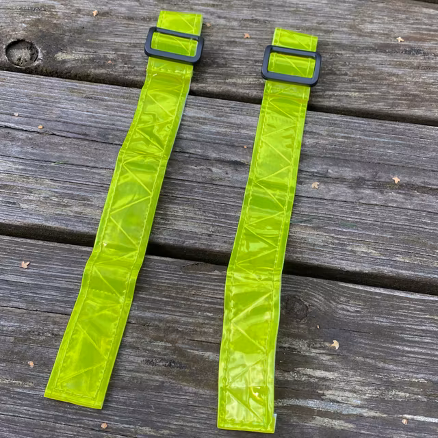 A pair of Reflective Stripes Yellow laying flat on wooded floor outside