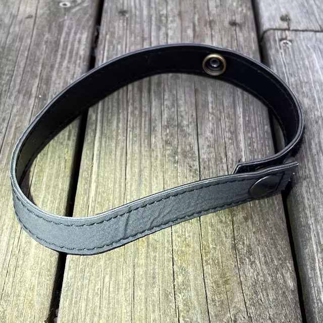 Reflexband Ankel Taktiskt Svart från TAC-UP GEAR ihopknäppt på trägolv med ljus på i dagsljus