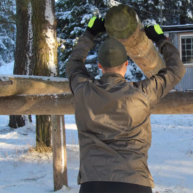 Lifting outdoors at the training area wearing a Running Jacket Green.