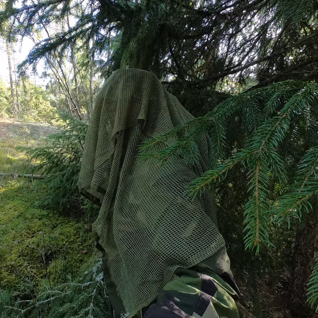 Showing the excellence in camouflage wearing a draped Scrim Net Scarf Green draped and in the Swedish forest