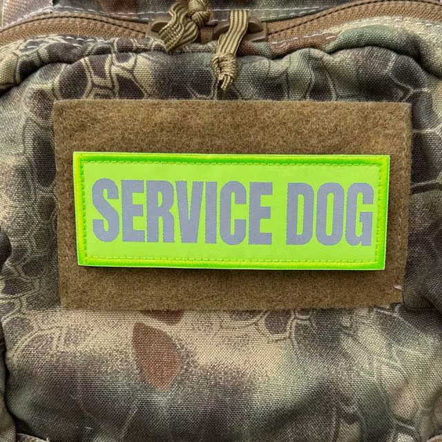 Service Dog HiVis PVC Patch mounted on a camouflage backpack, close-up