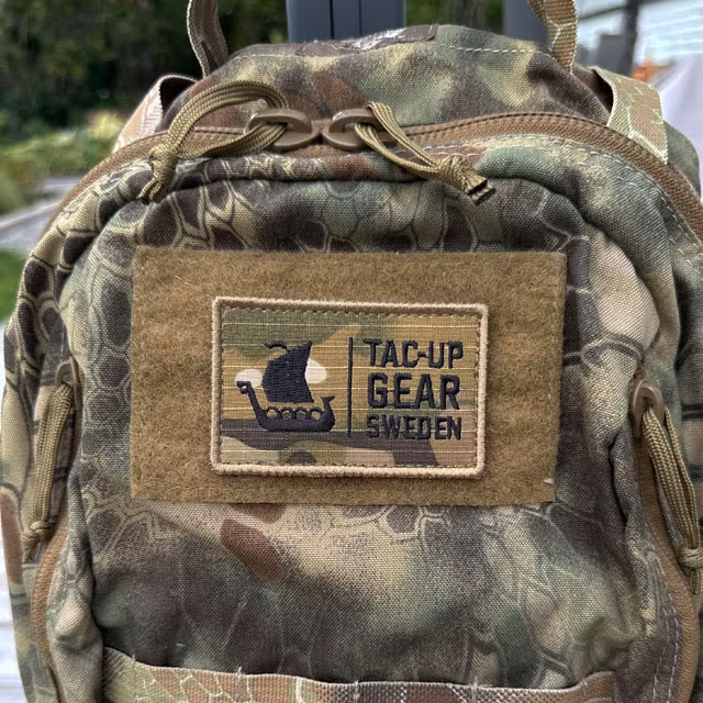 TUG Multicam Hook Patch mounted on a camouflage backpack, close-up