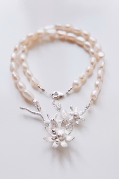 Silverkvist med blommor på pärlhalsband