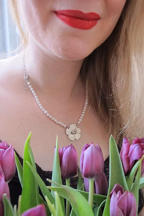Silverblomma på halsband av pärlor och kedja
