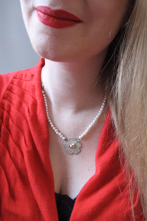 Silverblomma på halsband av pärlor och kedja