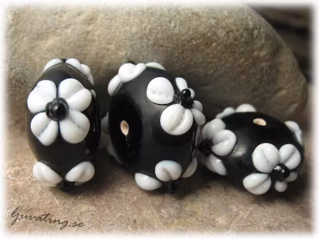 Svart med vita blommor ca 24x12 mm