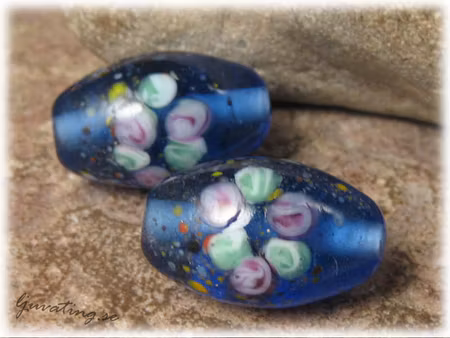 Transp blå oval pärla med blommor ca 23x14 mm