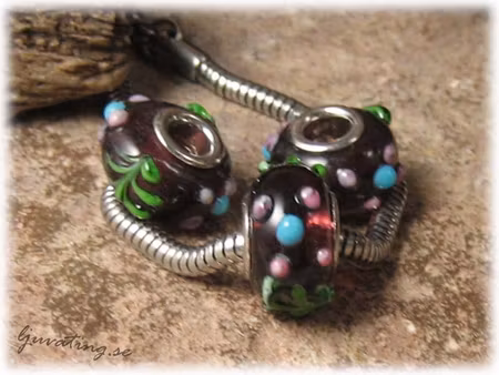 Ormlänkspärla mörk plommon med blommor ca 15x10 mm