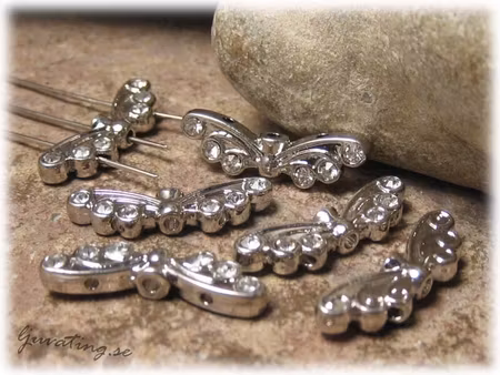 Vinge med snirklar och clear strass ca 22x7 mm