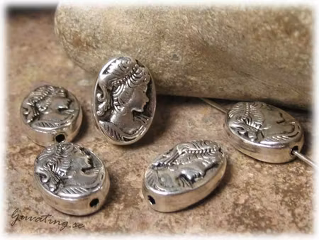 Oval flat metallpärla med kvinnohuvud ca 14x10 mm