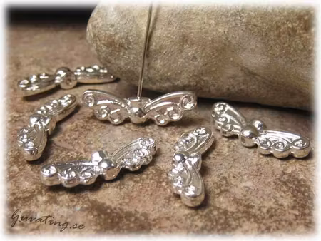 Blank vinge med snirklar ljus silverfärg ca 22x7 mm