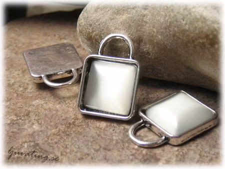 Berlock med vit cats eye pärla ca 21x15 mm