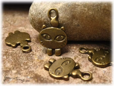 Berlock katthuvud med ben i bronsfärgad metall ca 18x12 mm